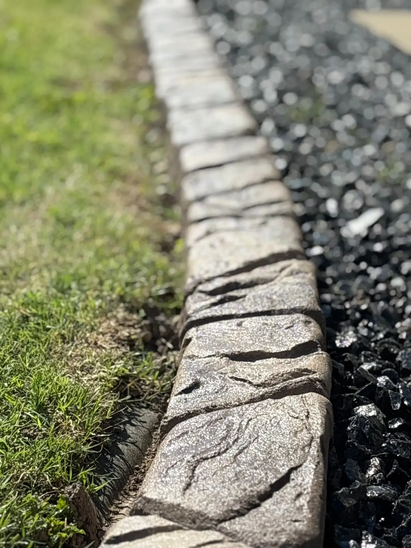 Decorative stamped concrete curbing edging a finished landscape bed.
